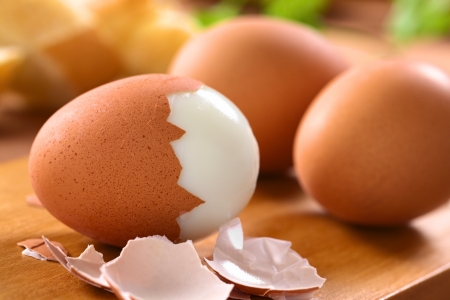 Fresh hard boiled eggs with shell beside on wooden board  Selective Focus, Focus on the front of the shell on the first egg の写真素材