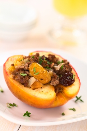 Savory baked apple filled with mincemeat, raisins, sultanas, onion and walnut, sprinkled with fresh thyme leaves on top (Selective Focus, Focus on the sultana in the front)   の写真素材