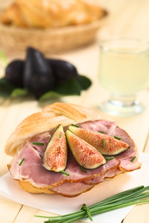 Fresh fig slices on smoked ham sandwich garnished with chives on sandwich paper (Selective Focus, Focus on the middle of the sandwich)の写真素材