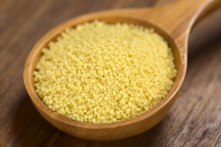 Raw couscous on wooden spoon (Very Shallow Depth of Field, Focus one third into the couscous)の写真素材