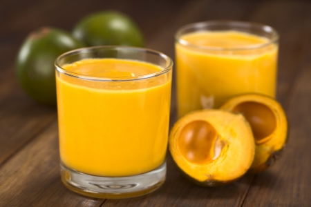 Milkshake made of the Peruvian fruit called lucuma  served in glass with lucuma fruits around の写真素材