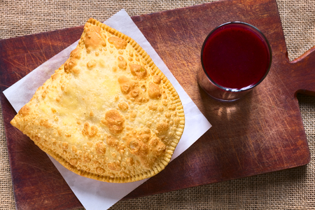 Traditional Bolivian snack called Pastel (deep-fried pastry filled with cheese) served with Api, a...