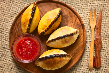 Overhead shot of traditional Bolivian savory pastries called Saltena filled with thick meat stew, which is a very popular street snack in Bolivia photographed with natural lightの写真素材