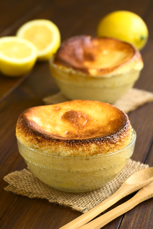 Homemade lemon souffle in glass bowls, photographed on dark wood with natural light (Selective Focus, Focus on the front of the first souffle)の写真素材