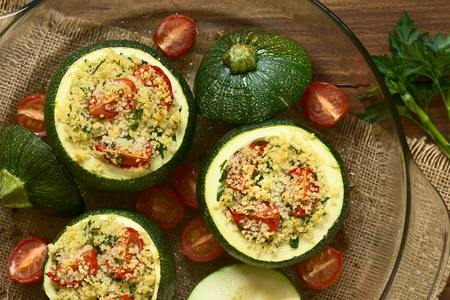 Baked round zucchini stuffed with couscous, cherry tomato and parsley, photographed overhead with natural light (Selective Focus, Focus on the top of the stuffed zucchinis)の写真素材