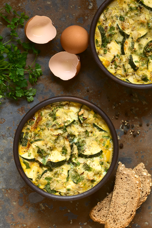 Frittata with zucchini and parsley in rustic bowl, photographed overhead on slate with natural lightの写真素材