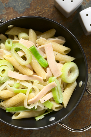 Pasta dish with ham and leek in cream sauce served in bowl, photographed overhead on slate with natural light (Selective Focus, Focus on the top of the dish)の写真素材