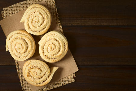 Freshly baked sweet coconut rolls, photographed overhead on dark wood with natural light (Selective Focus, Focus on the top of the rolls)の写真素材