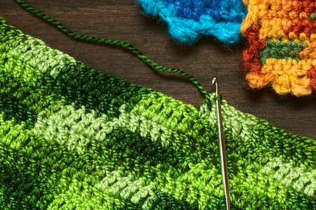 Crochet handicraft, making a place mat out of green yarn with a pattern of double stitches using a...