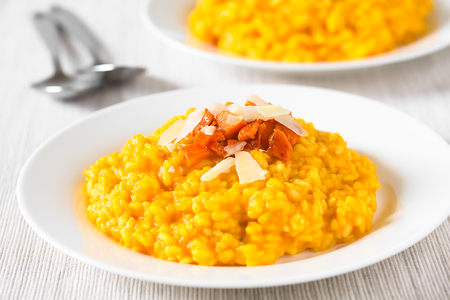 Fresh homemade carrot risotto made with pureed carrot, garnished with roasted carrot and hard cheese, photographed with natural light (Selective Focus, Focus in the middle of the image)の写真素材