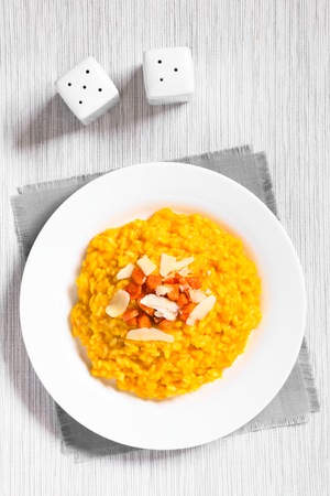 Fresh homemade carrot risotto made with pureed carrot, garnished with roasted carrot and hard cheese, photographed overhead with natural light (Selective Focus, Focus on the top of the risotto)の写真素材