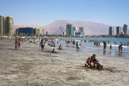 IQUIQUE, CHILE - JANUARY 23, 2015: Unidentified people enjoying the water and playing in the sand on the crowded Cavancha beach on January 23, 2015 in Iquique, Chile. Iquique is a popular beach town and free port city in Northern Chile.のeditorial素材