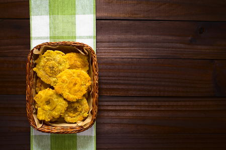 Patacon or toston, fried and flattened pieces of green plantains, a traditional snack or accompaniment in the Caribbean, photographed overhead on dark wood with natural lightの写真素材