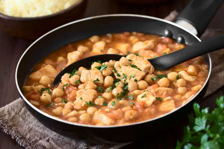 Chicken and chickpea stew or tagine in skillet, parsley on top, couscous in the back, photographed with natural light (Selective Focus, Focus in the middle of the image)の写真素材