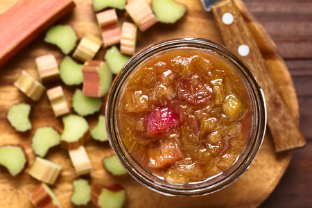 Homemade rhubarb jam in jar with raw cut rhubarb on the side, photographed overhead (Selective Focus, Focus on the jam)の写真素材