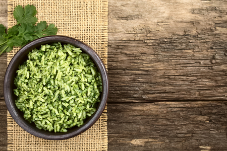 Traditional Mexican Arroz Verde green rice dish made of long-grain rice, spinach, cilantro and garlic, served in rustic bowl, photographed overhead with copy space (Selective Focus, Focus on the rice dish)の写真素材