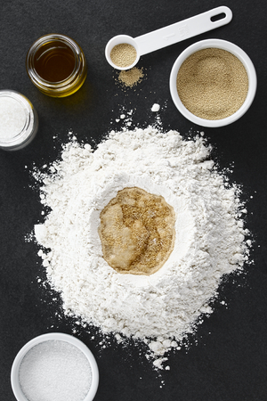 Preparing yeast dough for bread or pizza baking, photographed overhead on slateの写真素材