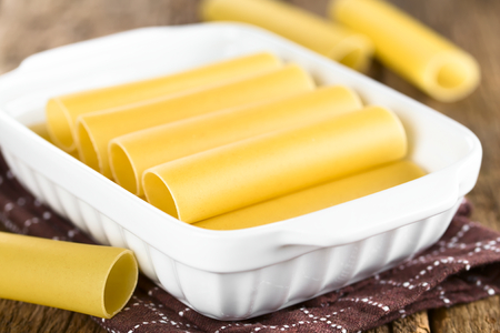 Raw cannelloni pasta in baking dish (Very Shallow Depth of Field, Focus on the left front edge of the first cannelloni in the dish)の写真素材