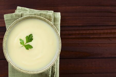 Fresh homemade cream of potato soup in bowl garnished with parsley leaf, photographed overhead with copy space on the right side (Selective Focus, Focus on the soup)の写真素材