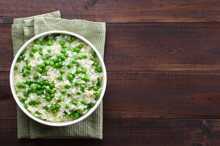 Fresh homemade creamy green pea risotto in bowl, photographed overhead with copy space on the sideの写真素材