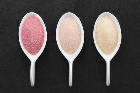 Red, orange and yellow instant jelly  powders on small spoons, photographed overhead on slate