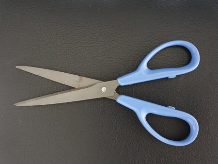 Blue scissors on black leather background, closeup of photo with shallow depth of fieldの写真素材
