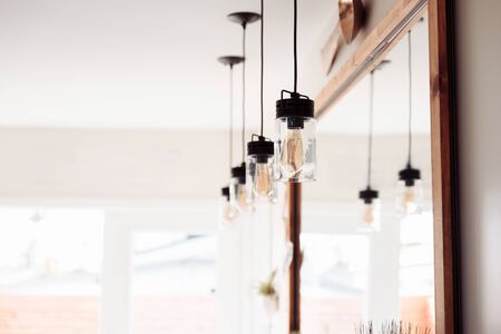 Four brass modern industiral ceiling lights hanging in front of the mirrow and reflecting in it