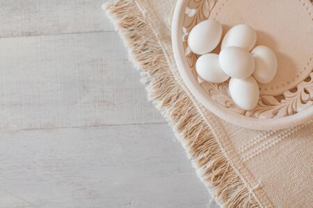 White eggs in hand made white plate on natural cotton table runner and stressed wooden tableの写真素材