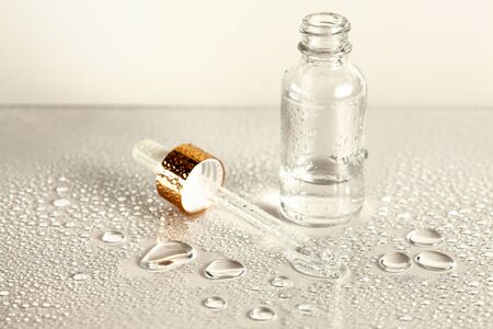 Clear glass bottle with medicine pipette on white background with water dropsの写真素材