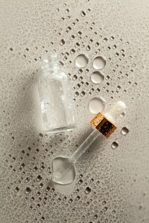 Clear glass bottle with medicine pipette on neutral  with water dropsの写真素材