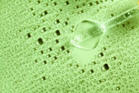 Green background with medicine pipette and liquid splashesの写真素材