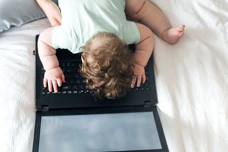 Mother and baby working on the laptop on the bed in bedroomの写真素材