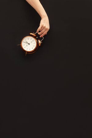 Hand holding bronze watch on black paper background.の写真素材