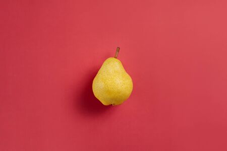Ripe yellow pear isolated on red and orange background.の写真素材