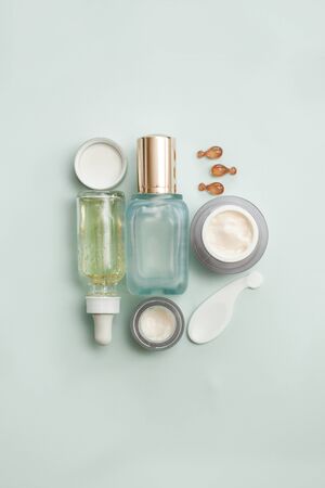 Face serum bottle with face creams, face oil capsules on light teal background. cosmetics flat lay.の写真素材