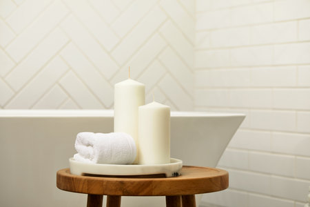 White bathroom with wooden table, marble tray, white candles and face towel. Bath tab with copy...