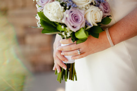 CLose up of brideholding wedding bouquet with white, cream and violet roses, Out of focus background wtih copy space.の写真素材
