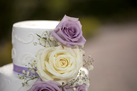 Three tiered wedding cake with lilac and cream roses and purple ribbonの写真素材