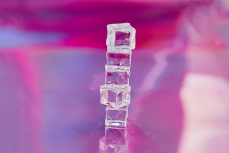 ice cubes on a reflective surface with pink background, close-upの写真素材