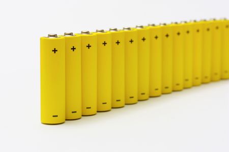 row of yellow anonymous alkaline batteries isolated on white backgroundの写真素材