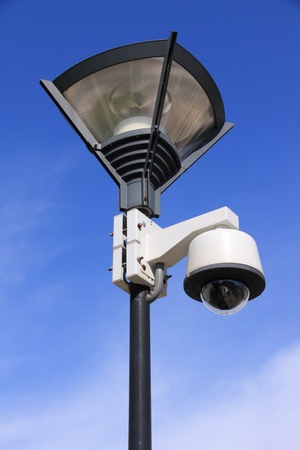 security camera on street lamp over blue sky