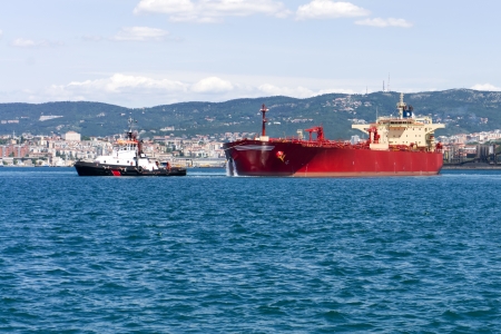 commercial cargo ship heading for port by tug boatの写真素材