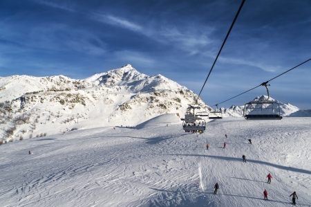 chairs on ski lift above a slope in high mountainの写真素材