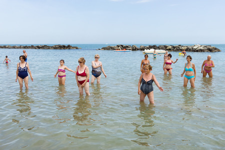CATTOLICA, ITALY - JUNE 23: aquagym on the beach on June 23, 2014 in Cattolica, Emilia Romagna, Italy. A group of seniors doing gymnastics in the morning on the beach.のeditorial素材
