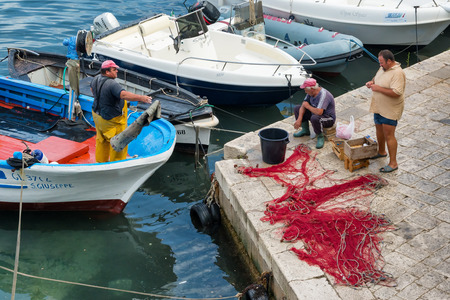 GALLIPOLI , ITALY - CIRCA JULY 2014: Harbor with fishermen, fishing ships and net. Professional fishing is a typical activity in the old townのeditorial素材