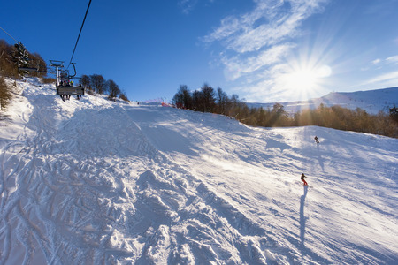 Ski lift over slopes in mountain with paths from skies and snowboardsの写真素材