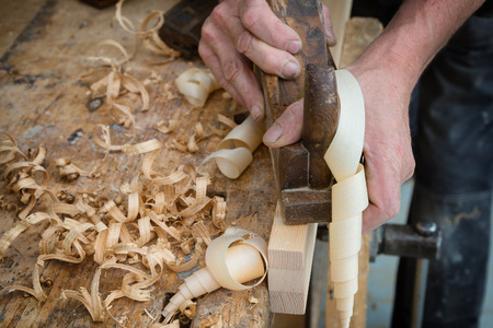 Senior woodworker or carpenter doing woodworking on a plank of wood in workshop with manual plane