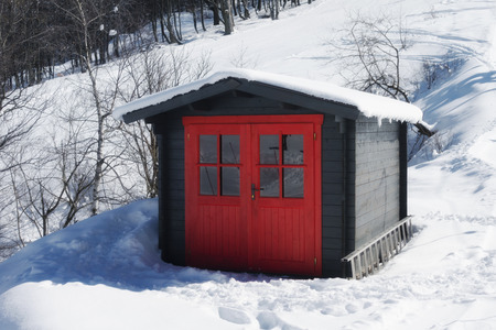 vivid red hut on snow covered mountain in winterの写真素材