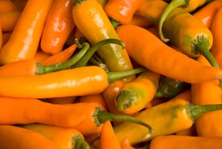 A bunch of orange peppers in a marketの写真素材