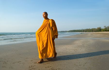 A Thai Buddhist Monk walking on the beach in the early morning sunの写真素材